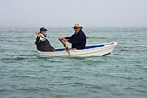 Couple in a small rowing boat in fog close to St. Martin's, Isles of Scilly, UK, June 2011. Model released.