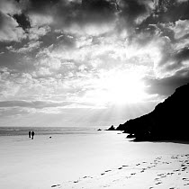 Silhouetted people walking along Three Cliffs Bay, Gower Peninsula, South Glamorgan, Wales, January 2012. No release available.