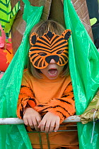 Child dressed in a tiger costume taking part in tropical rainforest play as part of a Folk Festival, celebrating the life of a forest and its people, documenting the threat from loggers and its immine...