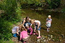 Children playing in River Onny,understanding nature by gathering river stones make oven for pizzas,Shropshire,England,UK, 2011