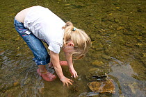 Girl playing in River Onny,understanding nature by gathering river stonesmake oven for pizzas,Shropshire,England, UK 2011
