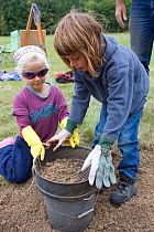 Adults and children making clay out of soil in order to make clay oven to make pizzas,learning how to use nature in a positive way,Shropshire, UK 2011