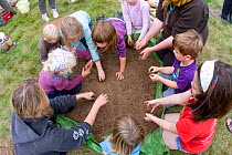 Adults and children making clay out of soil in order to make clay oven to make pizzas,learning how to use nature in a positive way,Shropshire, UK 2011