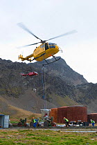 Helicopter taking off with bait bucket after refueling, second helicopter waiting for refueling, South Georgia Heritage Trust Rat Eradication Project, Grytviken, South Georgia, March 2011