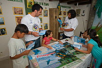 Conservation officers and children reading educational leaflets at the headquarters of the Programme for the Conservation of the Blue throated / Wagler's macaw (Ara glaucogularis) Trinidad, Beni, Boli...