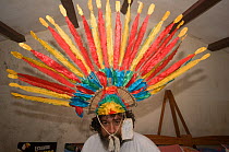 Conservation officer wearing a Macaw headress at headquarters of the Programme for the Conservation of the Blue throated / Wagler's macaw (Ara glaucogularis) Trinidad, Beni, Bolivia, Critically endang...