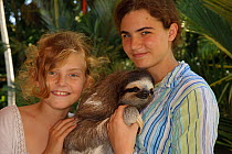 Two girls with tame Three-toed Sloth (Bradypus variegatus), 'Buttercup'.   Aviarios del Caribe Sloth Sanctuary, Costa Rica, 2008.