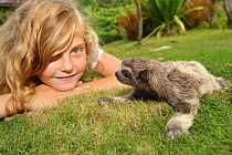 Child looking at baby Brown-throated Three Toed Sloth (Bradypus variegatus) on lawn at the sloth orphanage.   Aviarios del Caribe Sloth Refuge, Costa Rica, 2008.