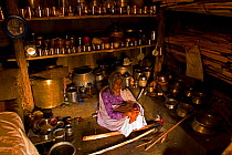 An elderly Toda woman sits inside her hut preparing a meal of raagi on a traditional wood-burning stove. Todas are strict vegetarians and their diet consists largely of plant and milk products. Wester...