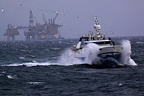 Fishing trawler 'Harvest Hope' with Buzzard oilfield in the background. North Sea, Europe, February 2012. All non-editorial uses must be cleared individually.
