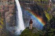 Photographer by the Haifoss waterfall with a rainbow in the spray, Iceland, August 2010