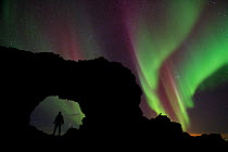 Person standing silhouetted in lava formation with northern lights above, Dimmuborgir, Myvatn, Iceland, March 2011