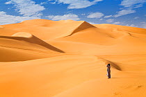Man standing amongst sand dunes in the Libyan desert, Sahara, Libya, North Africa, December 2007. No release available.