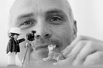 Photographer Klause Echle with toy figurines of a photographer and a cat-like animal.