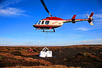Helicopter dropping load onto moorland.