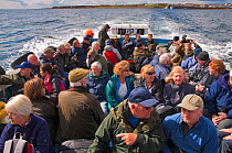 Tourists on tour boat heading out to the Farne Islands from Seahouses Harbour, Northumberland