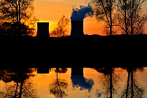 Nuclear power station in silhouette at sunrise with reflection in water, Cattenom, France, April 2009.