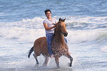 Boy riding Arabian gelding bareback through sea, Ojai, California, USA, model released