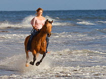 Girl riding Arabian gelding through waves, Ojai,  California, USA, model released