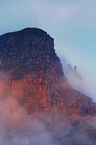 The rugged cliffs of Stac Pollidh in cloud and mist and lit by evening light. Cairngorms National Park, Scotland, July.