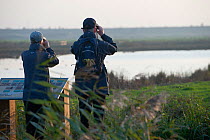 Two Birdwatchers looking over Rainham Marshes RSPB reserve, Essex, England, UK, November.