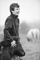 Young volunteer stroking pony, RSPB Vange Marshes reserve, Basildon, Essex, England, UK, November 2011. Model released.