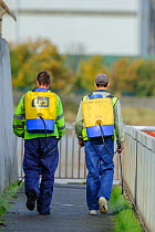 Men spraying herbicide on the Thames River Pathway, London, England, UK, December.