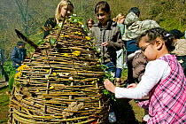 Asylum seeker children decorating wicker Easter egg with wildflowers on Easter Sunday to learn about natural world, Wales, April 2009.