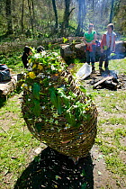 Asylum seeker group sitting around fire in woodlands after decorating whicker easter egg with wildflowers on Easter Sunday, Wales, April 2009.