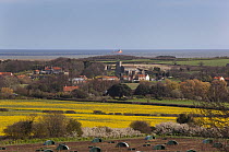 Looking across countryside to villages of Cley and Wiveton from Wiveton Downs, North Norfolk, UK, April 2012. Free-range pig unit in foreground and sea in distance,