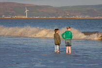 Children standing in shallows of sea, Swansea Bay, Wales, UK 2009 No MR so not sent to website