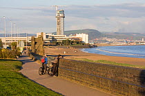 Couple enjoying cycle track alongside beach in urban environment, Swansea Bay, Wales, UK 2009