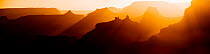 Rays of light from the setting sun filters through the temples and buttes of the canyon with the silhouetted spires of Angel's Gate in right foreground, Grand Canyon National Park, Arizona, USA