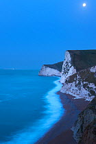 Moonlight on the Jurassic Coast, with Durdle Door and Portland beyond, Dorset, England, UK. November 2011.
