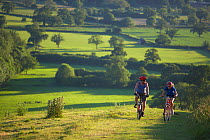 Man and woman on mountain bikes cycling on Hambledon Hill above the Blackmore Vale, Dorset, England, UK. June 2005.