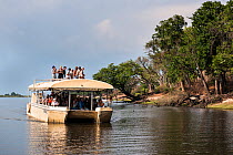 Tourists looking at wildlife from a dedicated viewing boat on the Chobe River, Botswana, November