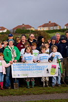 Children, volunteers and community members of tree planting project part of Breathing Spaces project in deprived area of Swansea with banners, Wales, UK, December 2009