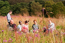 Young people having a picnic and making heart gestures at the camera, Luggiebank Wood SWT reserve, North Lanarkshire, Scotland, UK, August  2011