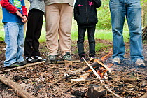 Five people standing next to a small fire on a bushcraft day, Palacerigg Country Park, Cumbernauld, North Lanarkshire, Scotland, UK, July  2011
