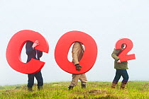People holding signs spelling CO2, representing carbon capture for peatland burial. Sutherland, Scotland, July 2012.