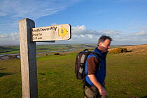 Man walking past South Downs Way long distance footpath signpost to Birling Gap at Seven Sisters Country Park, South Downs, England. |Model released