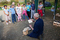 Man demonstrating birdbox building to children as part of Flora of the Fells day. Helvellyn, Lake District National Park, Cumbria, September.