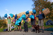 Litter picking volunteers holding bags of collected rubbish as part of Flora of the Fells conservation day. Helvellyn, Lake District National Park, Cumbria, September.