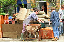 People trying to clear water after flooding, surrounded by flood damaged furniture, Ceredigion, Wales, UK, June 10th 2012