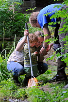 Family inspecting their catch after pond dipping during Abbots Pool and woodland reserve Bioblitz, Bristol, UK, June 2012. Model released.
