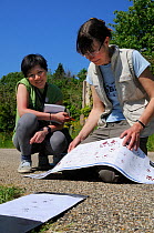 Volunteer Shen Yan Liow looks on as mammalogist Gill Brown matches up inky hedgehog footprints left in a footprint tunnel with identification chart during Arnos Vale Cemetery Bioblitz, Bristol, UK, Ma...
