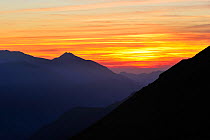 Mountain ranges silhouetted against sunset seen from the Col d'Aubisque in the Pyrenees-Atlantiques, Pyrenees, France, June 2012
