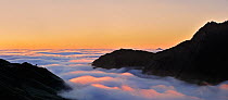 View over silhouetted mountains covered in mist at sunrise seen from the Col du Tourmalet, Pyrenees, France, June 2012