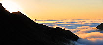 View over silhouetted chairlifts and mountains covered in mist at sunrise seen from the Col du Tourmalet, Pyrenees, France, June 2012