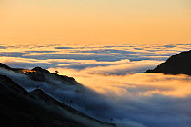 View over silhouetted chairlifts and mountains covered in mist at sunrise seen from the Col du Tourmalet, Pyrenees, France, June 2012